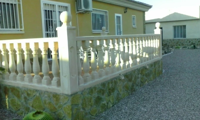 Foto de una casa con balaustrada en la escalera y bordeando el jardín frontal